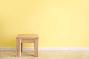 Renkli duvarın yanındaki küçük tahta masa.