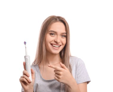 Beyaz arka planda elektrikli diş fırçası olan genç bir kadın.
