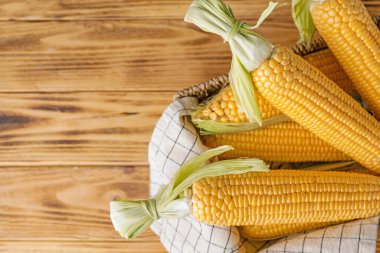 Masanın üzerinde taze mısır koçanı olan sepet.