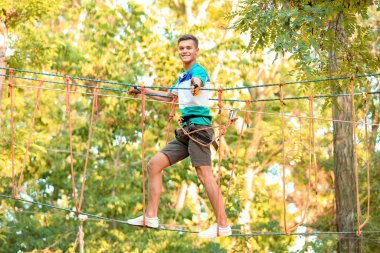 Ergen çocuk macera parkına tırmanıyor.