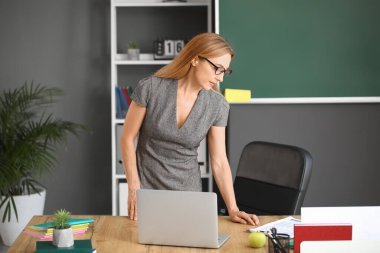 Olgun bayan öğretmen sınıfta ders veriyor.