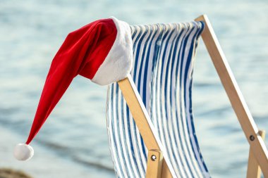 Deniz kıyısında Noel Baba şapkası takan bir güneşlik. Noel tatili konsepti