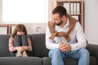 Ofiste üzgün küçük bir kızla çalışan erkek psikolog.