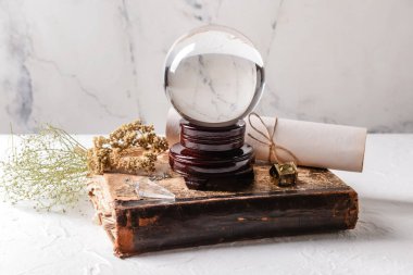 Kristal falcı küresi, büyü kitabı ve parşömen masanın üstünde.