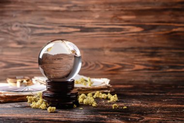 Kristal falcı küresi, büyü kitabı, kartlar ve ahşap masadaki kuru otlar.