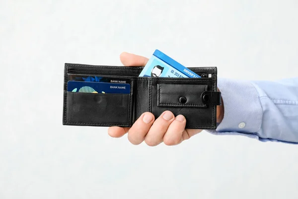 ライトの背景に財布の運転免許証を持つ男性の手 — ストック写真