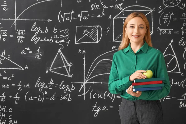 Mature maths teacher near blackboard in classroom