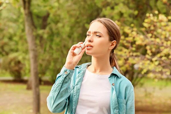 过敏的年轻女子在户外用鼻滴 — 图库照片