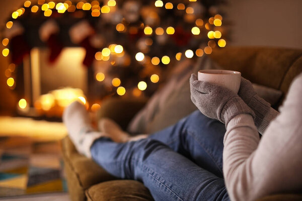 Beautiful young woman drinking hot chocolate at home on Christmas eve