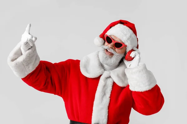 在灰色背景下听音乐的酷圣诞老人 — 图库照片
