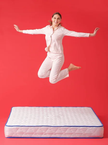 Young Woman Jumping Mattress Color Background — Stock Photo, Image