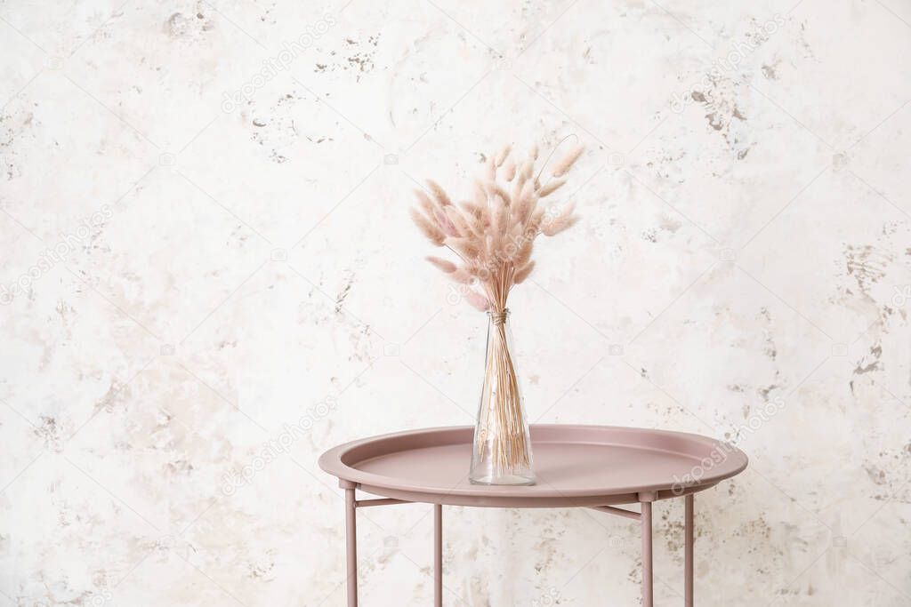 Table with vase near light wall
