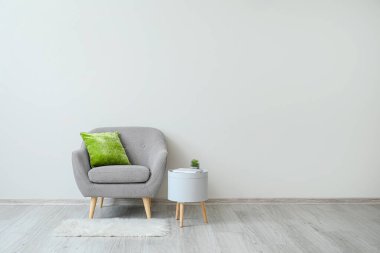 Yastıklı şık bir koltuk ve ışık duvarının yanındaki masa.