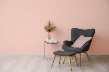 Yastıklı şık bir koltuk ve odanın duvarının yanında mumlarla dolu bir masa.