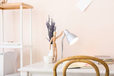 Odanın içinde ahşap mankenli bir masa.