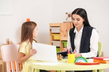 Evde küçük bir kızla çalışan kadın psikolog.