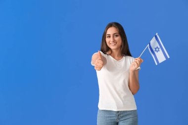 İsrail bayrağı taşıyan genç bir kadın arka planda başparmak kaldırıyor