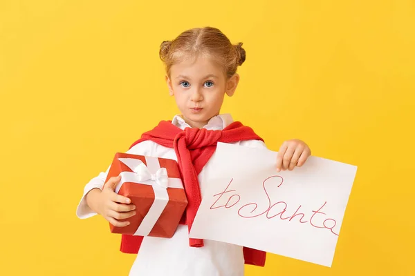 Kleines Mädchen Mit Weihnachtsgeschenk Und Brief Den Weihnachtsmann Auf Farbigem — Stockfoto