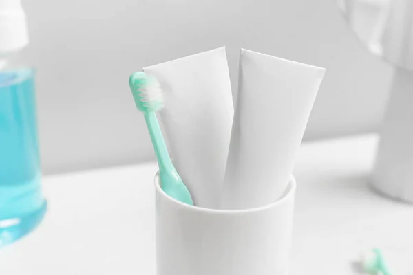 Holder with toothbrush and paste on table in bathroom