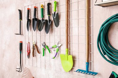 Duvarda farklı bahçe malzemeleri asılı.