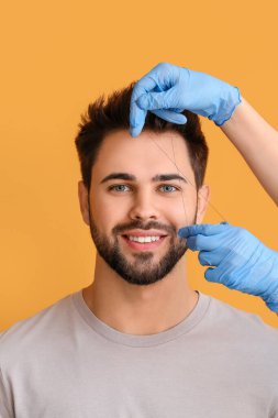 Genç adam renk arkaplanı üzerinde kaş düzeltme prosedüründen geçiyor