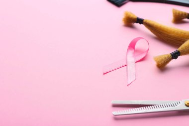 Kuaför aletleri ve arka planda pembe kurdele. Göğüs kanseri hastaları için saç bağışı kavramı