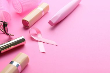 Renkli arka planda pembe kurdele ve kozmetik ürünleri. Göğüs kanseri farkındalığı konsepti