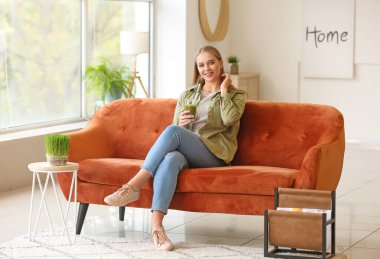 Genç bayan evde buğday suyu içiyor.