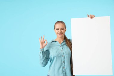 Boş posterli güzel genç bir kadın. Renkli arka planda iyi görünüyor.