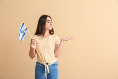 İsrail bayrağı taşıyan genç bir kadın renkli arka planda bir şeyler gösteriyor.