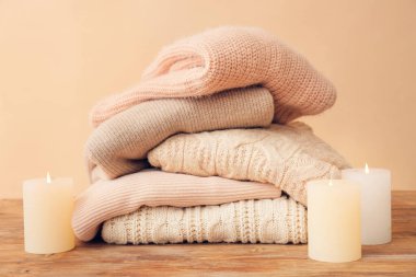 Masanın üzerinde renk arkaplanına karşı mumlar olan sıcak giysiler.
