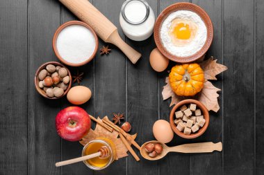 Koyu ahşap zemin üzerinde balkabağı turtası hazırlamak için malzemelerden yapılmış çerçeve