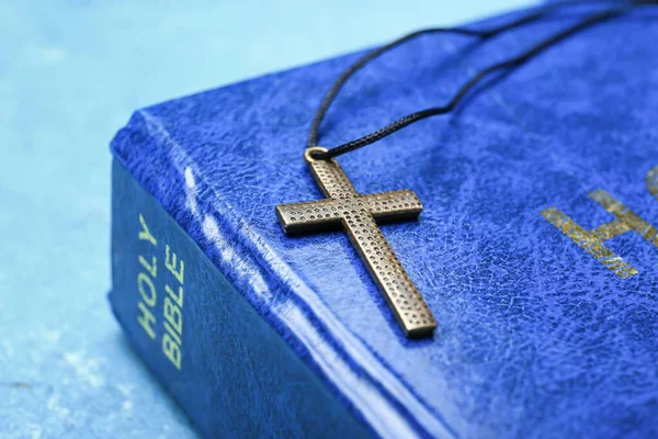 Holy Bible and cross on color background, closeup