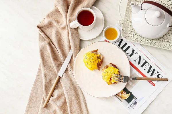 おいしい卵とプレートベネディクト テーブルの上の新聞やお茶 — ストック写真