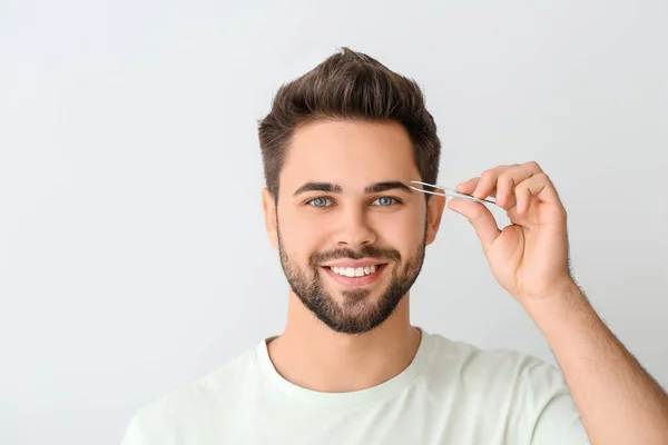 Jongeman Corrigeren Wenkbrauwen Lichte Achtergrond — Stockfoto