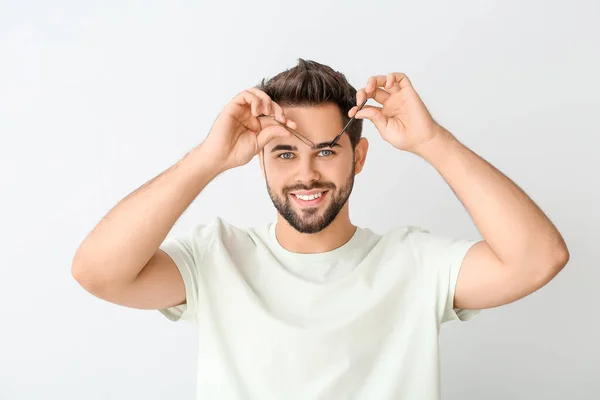 Jongeman Corrigeren Wenkbrauwen Lichte Achtergrond — Stockfoto