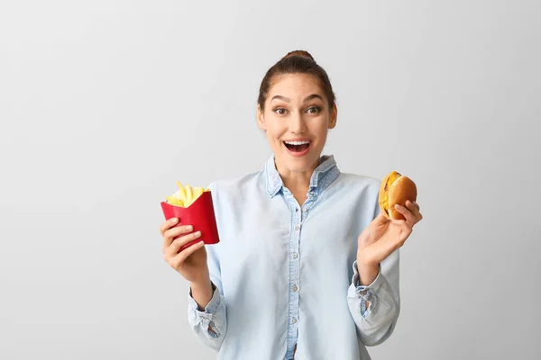 快乐的年轻女人 有薯条和汉堡包 背景浅薄 — 图库照片