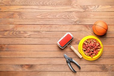 Hayvan bakımı aksesuarları ve ahşap arka planda kuru hayvan mamasıyla dolu bir kase.