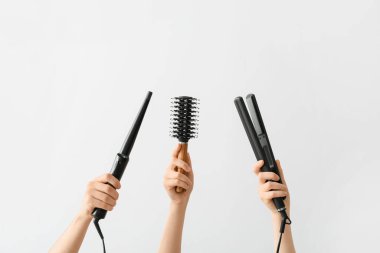 Hafif arka planda saç aletleri olan kadın eller.