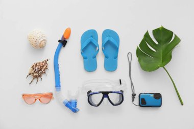 Dalış maskeli ve beyaz arka planda parmak arası terlikli plaj aksesuarları.