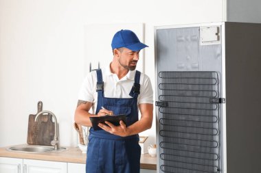 Mutfaktaki buzdolabının yanında tamirat işçisi.