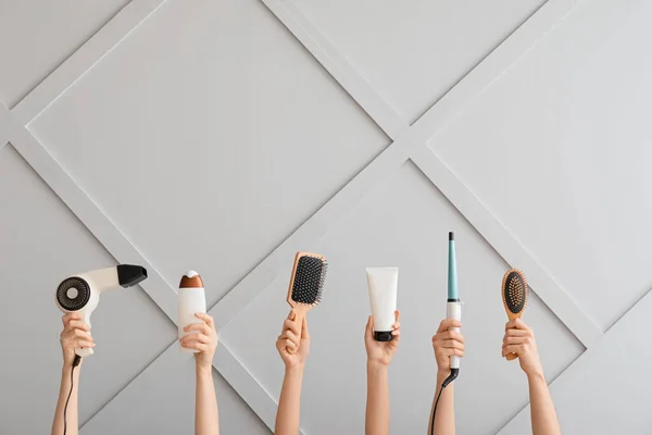 Female hands with hair tools on light background