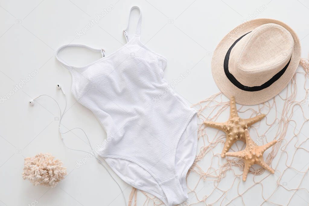 Female swimsuit with hat and seashells on white background