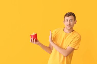Genç adam arka planda patates kızartması yemeyi reddediyor.