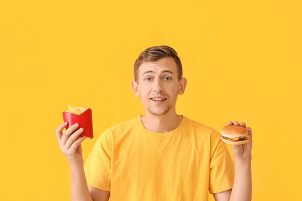 Joven Con Papas Fritas Hamburguesa Sobre Fondo Color —  Fotos de Stock