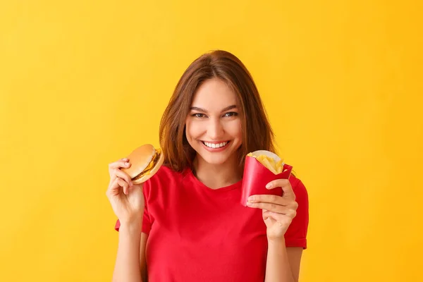 若いです女性とともにフレンチフライとハンバーガー上の色の背景 — ストック写真