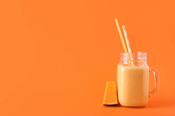 Mason jar of tasty pumpkin smoothie on color background