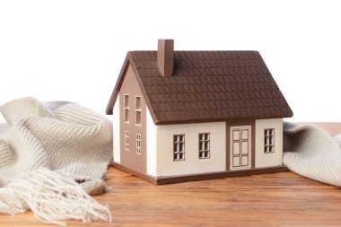 Beyaz arka planda masa üzerinde ev ve sıcak eşarp figürü. Isınma mevsimi kavramı