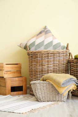 Yastıklı sepetler, ekose ve renkli duvarın yanındaki kutular.