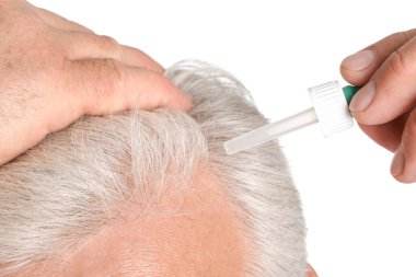 Beyaz arka planda saç dökülmesi tedavisi için serum kullanan yaşlı adam, yakın plan.